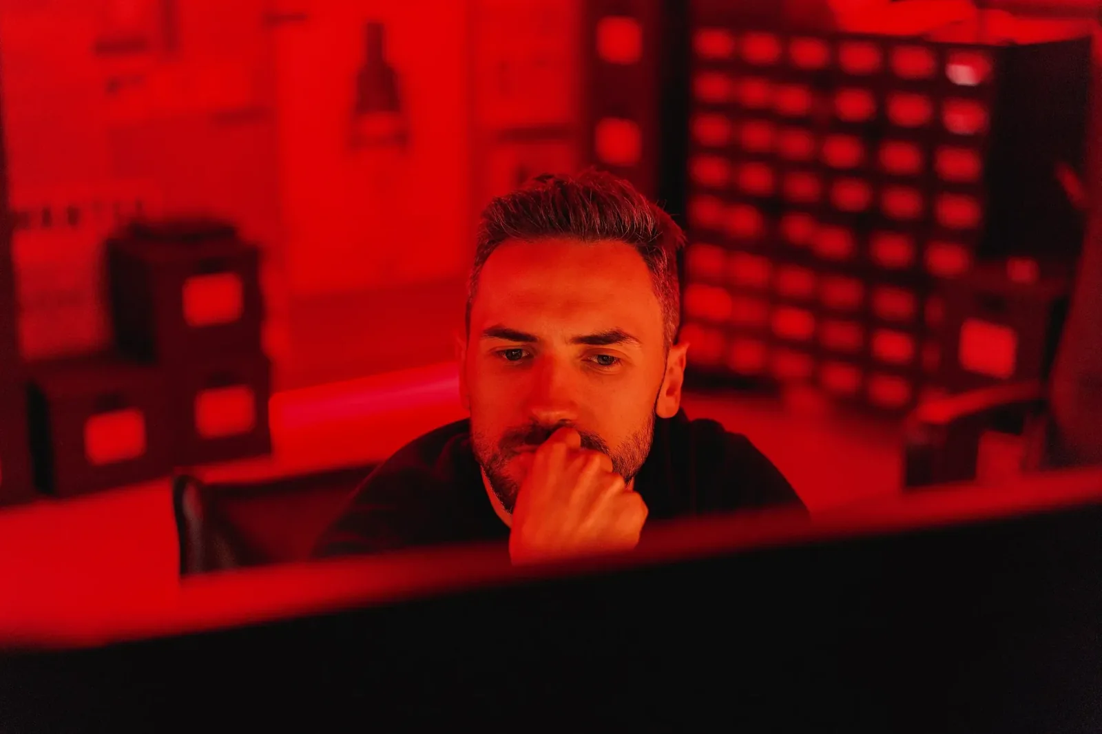 Marcin Myszka pracuje przy komputerze w czerwono oświetlonym pokoju