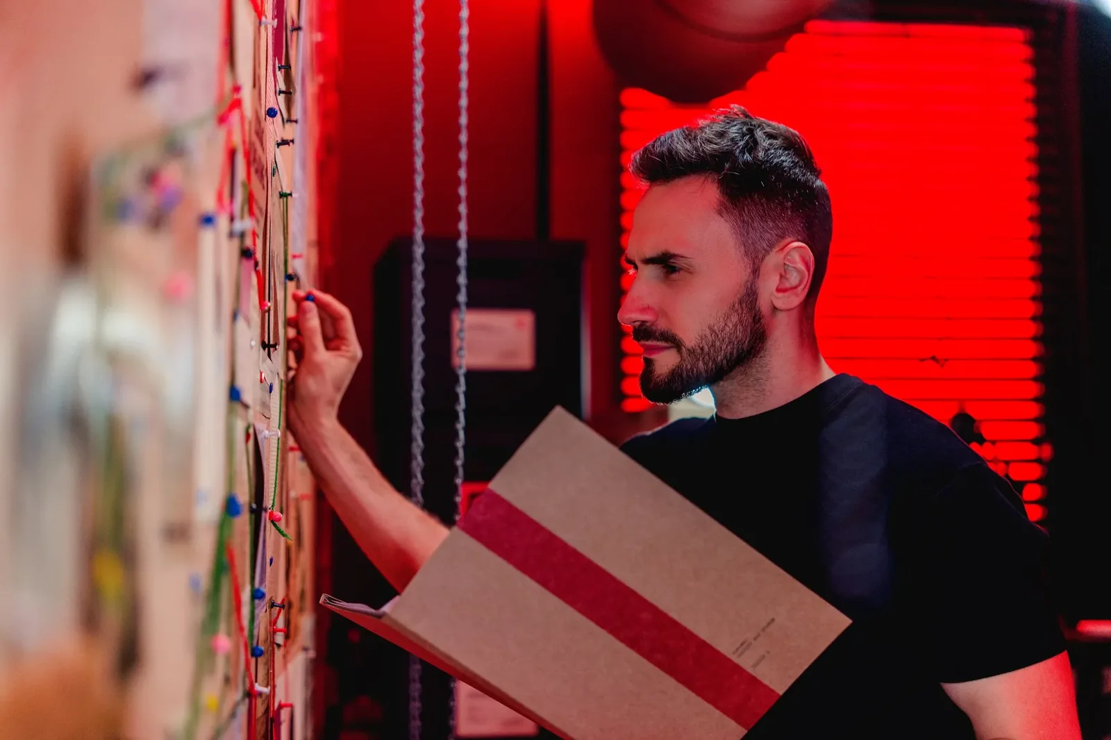 Marcin Myszka analizuje tablicę śledczą i trzyma teczkę z materiałami
